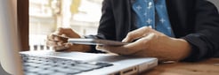 cropped-image-woman-inputting-card-information-key-phone-laptop-while-shopping-online