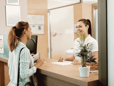 happy-woman-talking-receptionist-while-arriving-spa